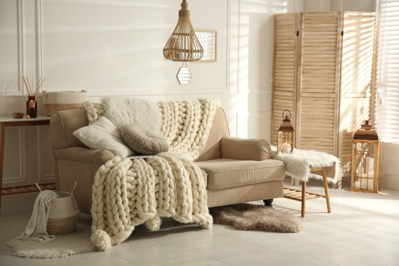 Hygge Einrichtung – Helles Wohnzimmer mit kuscheligen Decken.