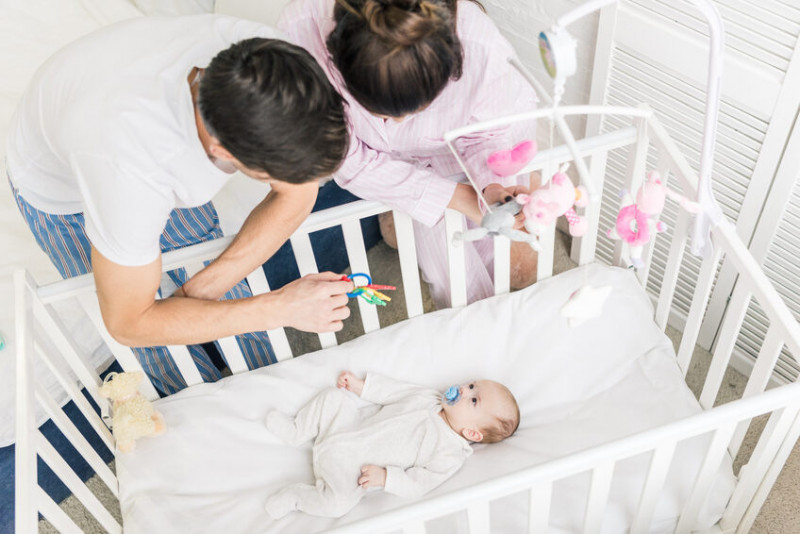Das richtige Babybett: Eltern beobachten Baby im Babybett