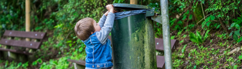 Kinder lernen von ihren Eltern: Ein Junge entsorgt Abfall im Mülleimer.